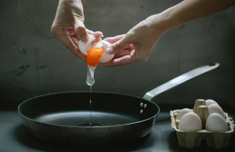 a person squeezing an egg into a frying pan, by Jessie Algie, pexels contest winner, process art, fan favorite, filling with water, sleek hands, longque chen