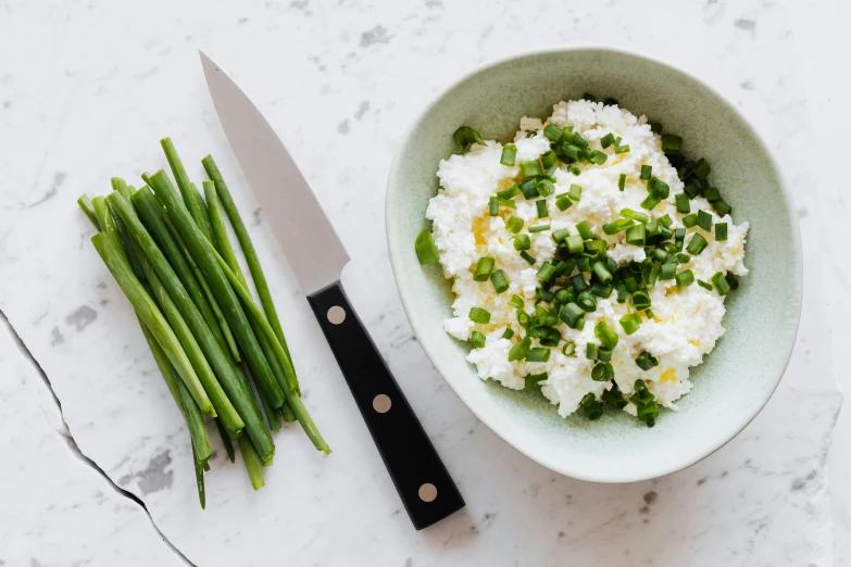 a bowl of rice and green beans next to a knife, unsplash, private press, cheeses, gypsophila, jen atkin, epicurious