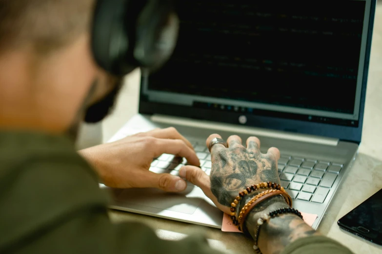 a man wearing headphones is typing on a laptop, a tattoo, trending on pexels, wearing shipibo tattoos, avatar image, jewelry, professional image