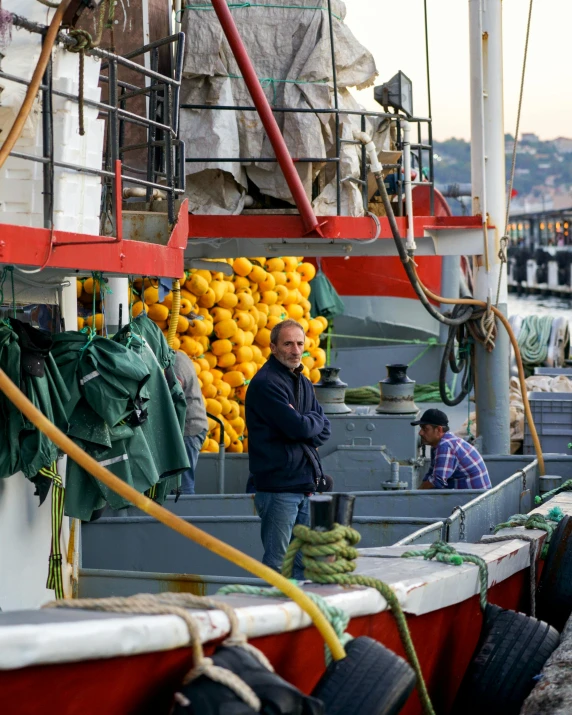 a man standing on top of a boat next to a bunch of oranges, ships in the harbor, trending photo, high-resolution photo, yellow