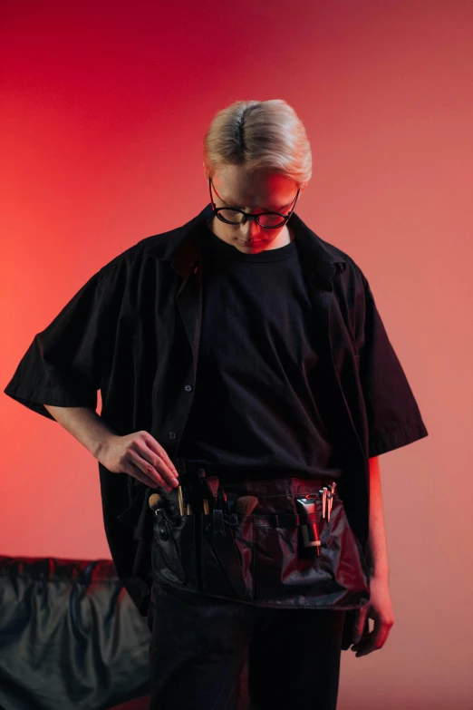 a man standing in front of a red wall, an album cover, inspired by Josef Abel, unsplash, neo-dada, wearing an ammo belt, johan liebert, 2 techwear women, in a black room