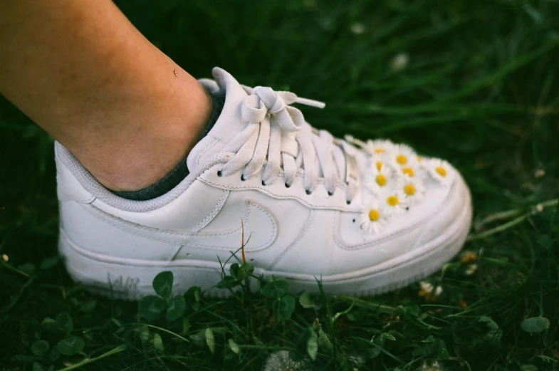 a close up of a person's shoes in the grass, inspired by Elsa Bleda, pexels contest winner, hyperrealism, head made of giant daisies, wearing white sneakers, air force, wearing studded leather
