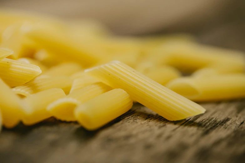 a pile of pasta sitting on top of a wooden table, a macro photograph, pexels contest winner, light stubble, vanilla, pikes, no cropping