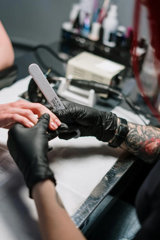 a woman getting her nails done at a salon, a tattoo, by Adam Marczyński, trending on pexels, hyperrealism, holding knife, synthetic bio skin, lgbtq, tatto