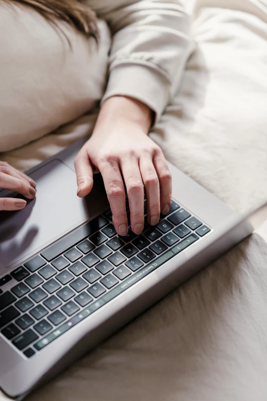 a woman laying in bed using a laptop computer, pexels, sleek hands, a photo of a man, smooth texture, professional grade