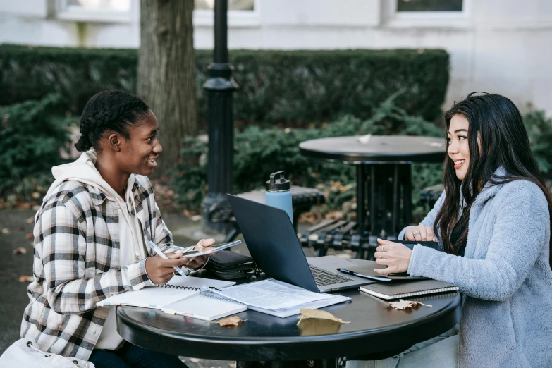 two women sitting at a table with laptops, trending on pexels, university, background image, diversity, al fresco