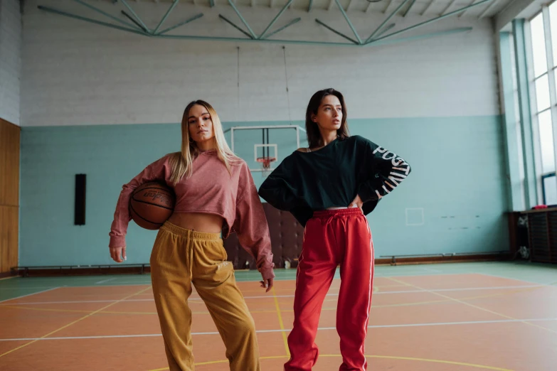 two women standing next to each other on a basketball court, trending on pexels, antipodeans, red shirt brown pants, vintage clothing, sweater, jovana rikalo