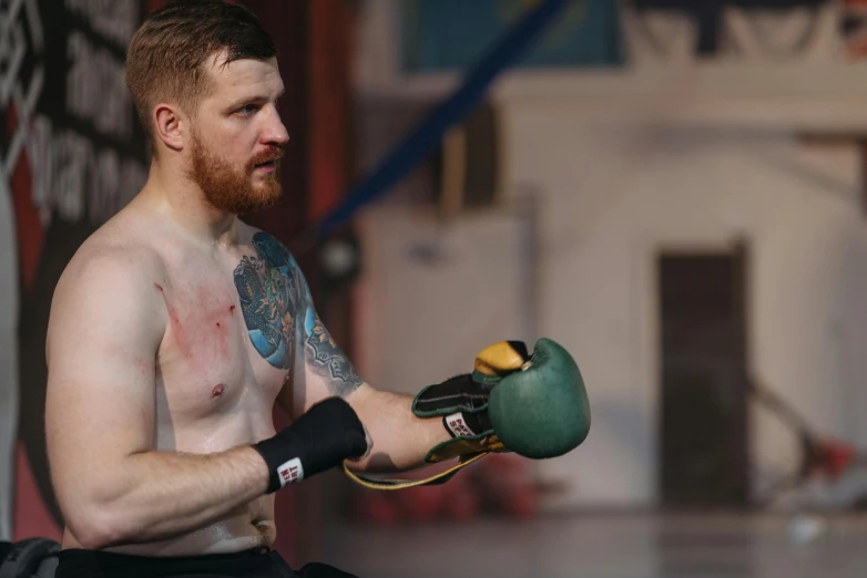 a man with a beard wearing boxing gloves, by Ilya Ostroukhov, pexels contest winner, hyperrealism, sam hyde, in a boxing ring, handling riffle on chest, slightly smiling