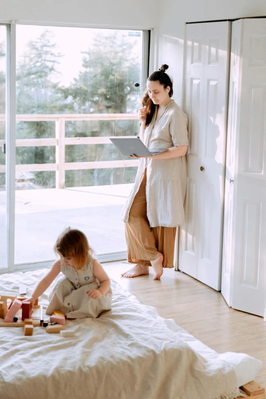 a woman standing next to a child on a bed, by Arabella Rankin, pexels contest winner, sitting on a mocha-colored table, in doors, designed for cozy aesthetics!, al fresco