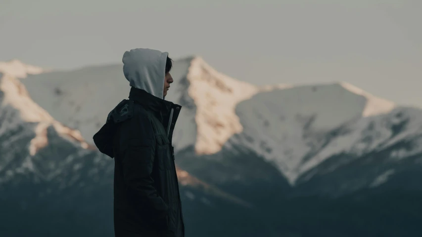 a person standing on top of a snow covered mountain, wearing a hoodie, profile shot, chill, trending photo