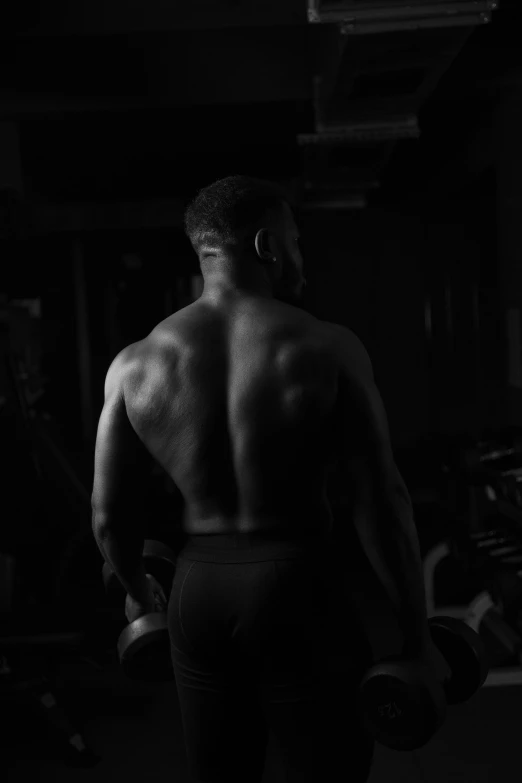 a black and white photo of a man in a gym, by Adam Marczyński, with his back turned, black man, dark and foreboding, barret frymire