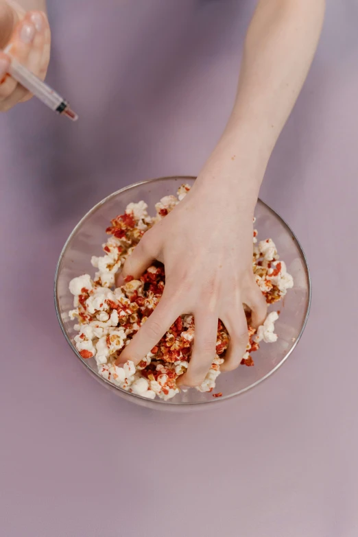 a person scooping popcorn into a bowl, by Lucette Barker, process art, her hands are red roots, promo image, gif, ingredients on the table