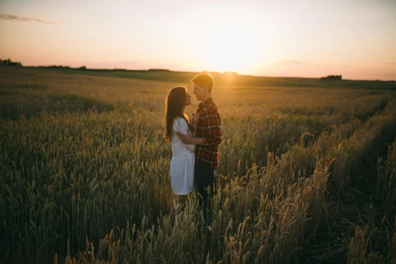 a couple standing in a field at sunset, pexels contest winner, attractive girl, slight stubble, romantic lead, plain background