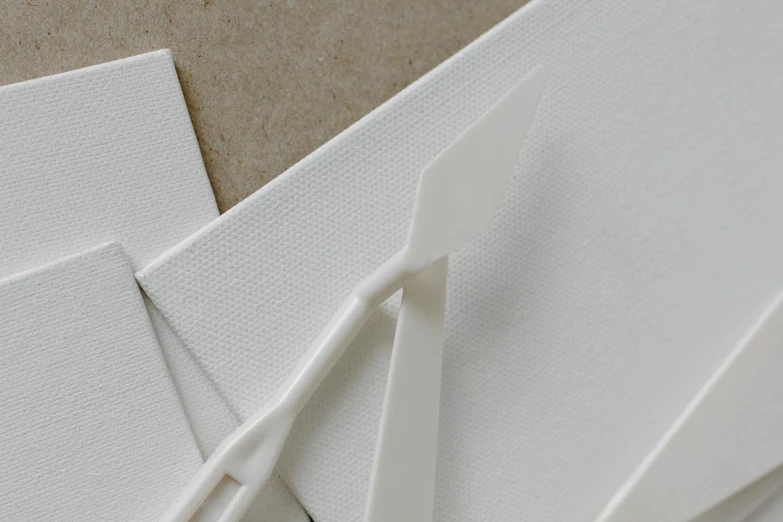 a pair of scissors sitting on top of a piece of paper, inspired by Zaha Hadid, linen canvas, detail, spatula, white finish