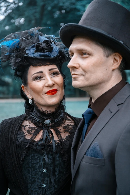 a man and a woman standing next to each other, a portrait, unsplash, international gothic, wearing a tophat, black and blue scheme, mid thirties, black and reddis