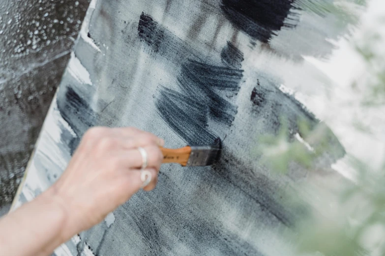 a person using a brush to paint a piece of art, inspired by Hans Hartung, unsplash, moonlight grey, gardening, grey, lacquer on canvas