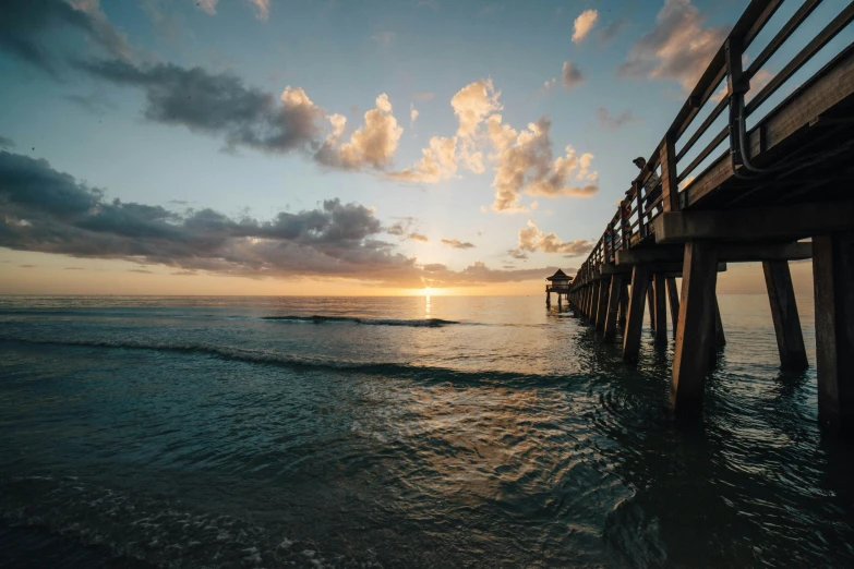 a pier stretches out into the ocean at sunset, by Niko Henrichon, pexels contest winner, renaissance, 2 5 6 x 2 5 6 pixels, tie-dye, slide show, a wooden