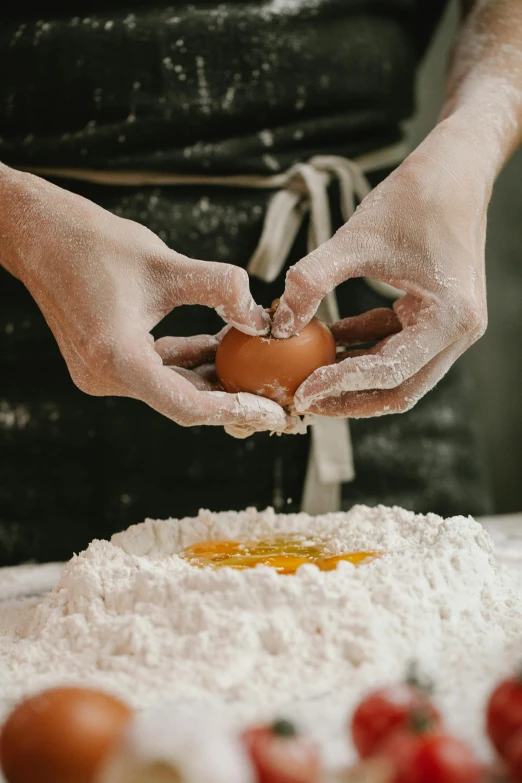 a person holding an egg on top of a table, covered in white flour, gourmet and crafts, pasta, carefully crafted