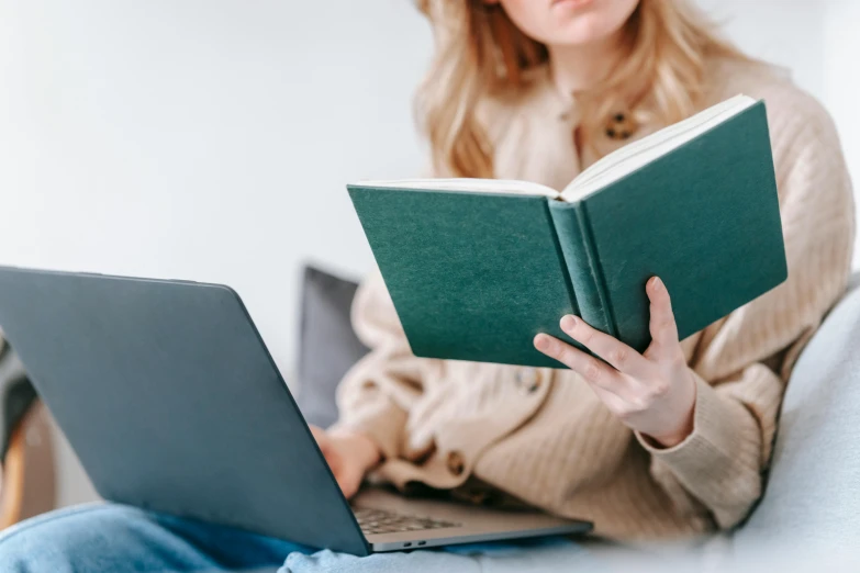 a woman sitting on a couch reading a book, a sketch, trending on pexels, laptops, with teal clothes, big open book, restoration