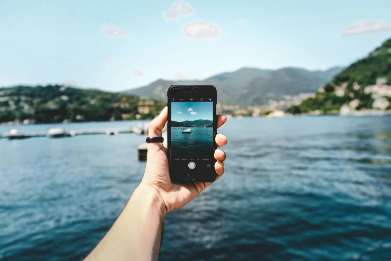 a person taking a picture of a body of water, iphone wallpaper, fan favorite, with water and boats, technologies