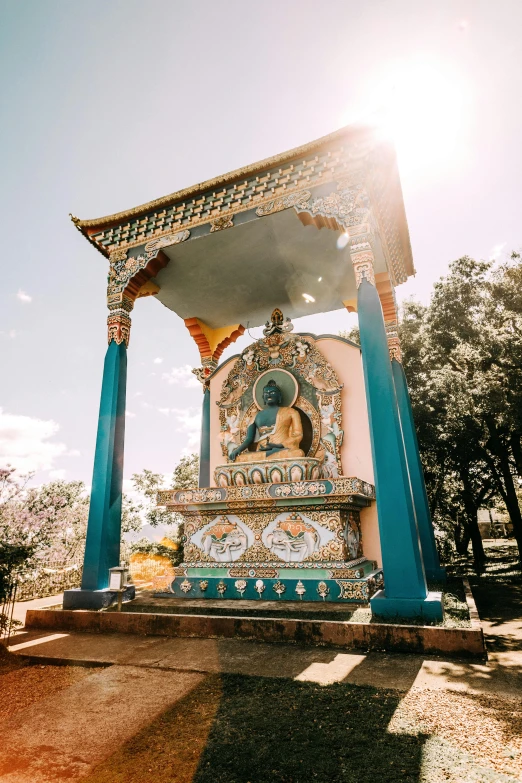 a statue sitting on top of a lush green field, trending on unsplash, cloisonnism, tibetan inspired architecture, sunny light, shrine, blue