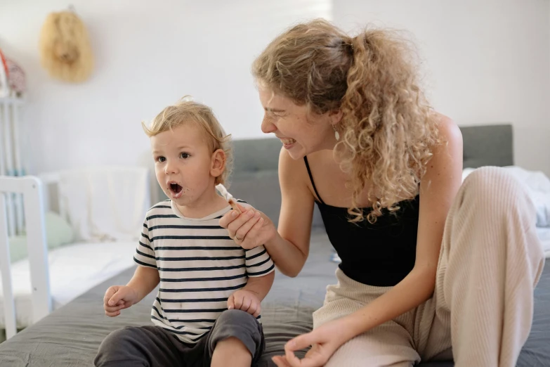 a woman brushing a baby's teeth while sitting on a bed, pexels contest winner, art & language, earing a shirt laughing, manuka, kid named finger, little boy