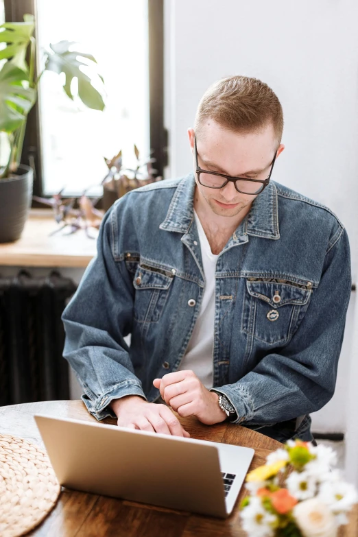 a man sitting at a table working on a laptop, trending on pexels, arbeitsrat für kunst, wearing double denim, wearing black rimmed glasses, hr ginger, decorative