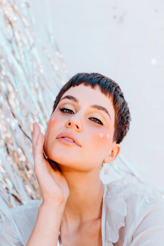 a woman in a white shirt posing for a picture, an album cover, by Julia Pishtar, trending on pexels, short black pixie cut hair, transparent vibrant glowing skin, glittery, kailee mandel