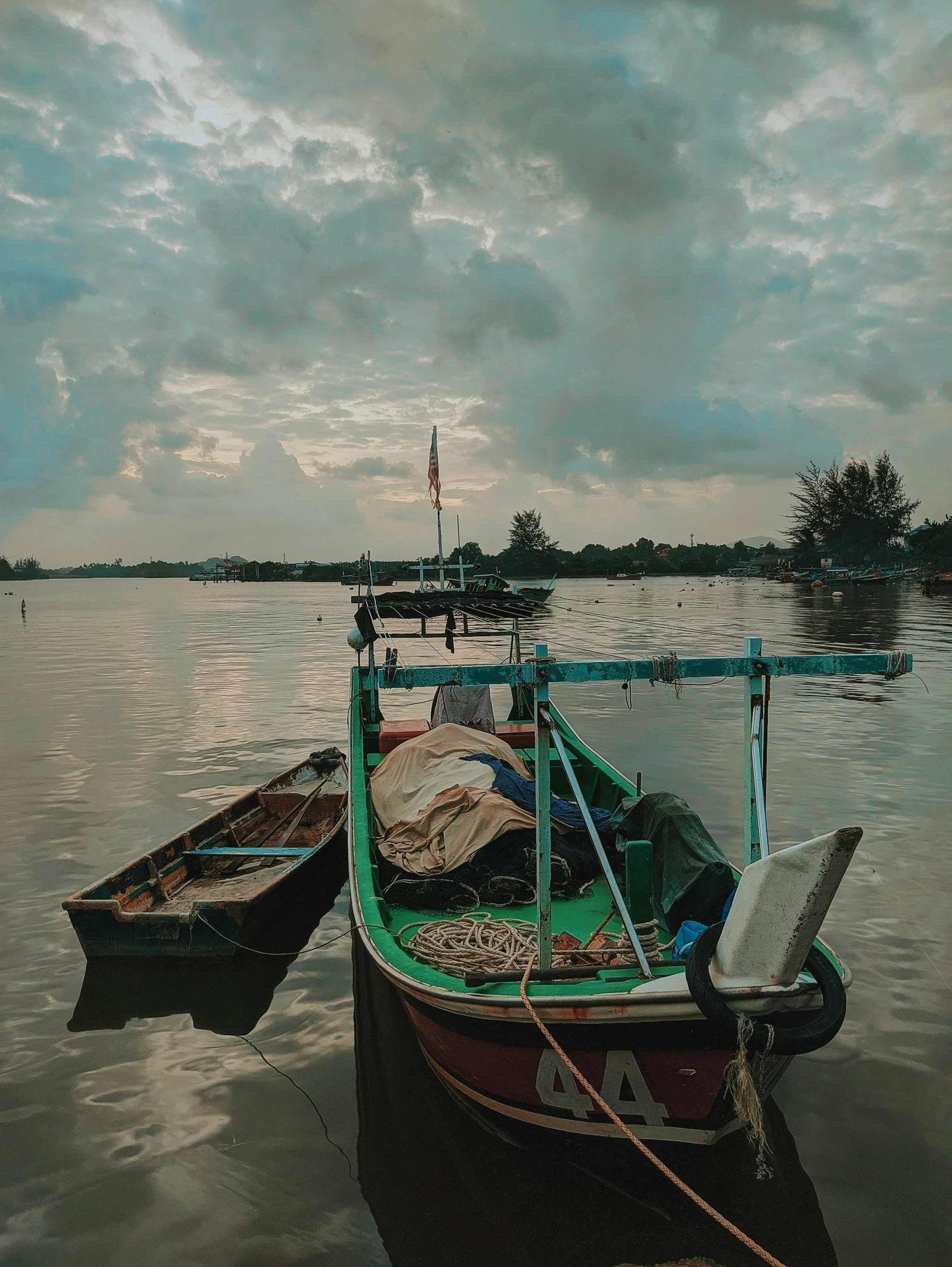 a couple of boats sitting on top of a body of water, a picture, pexels contest winner, sumatraism, moody sky at the back, album art, fishing town, photo on iphone