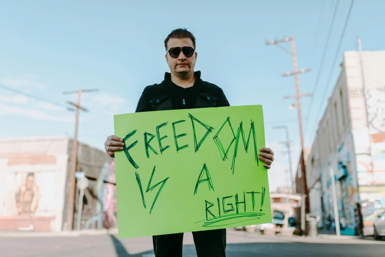 a man holding a sign that says freedom is a right, an album cover, pexels, profile pic, image, artem, sight