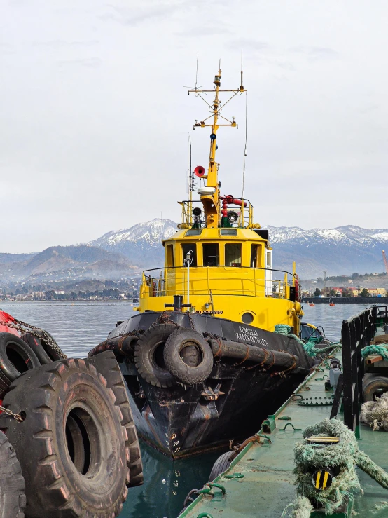 a large yellow boat sitting on top of a body of water, auto-destructive art, reykjavik, heavy machinery, with mountains in background, low quality photo