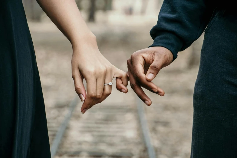 a close up of two people holding hands on a train track, trending on pexels, “diamonds, celebrating an illegal marriage, attractive girl, diverse