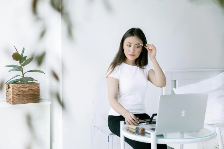 a woman sitting at a table with a laptop, trending on pexels, beautiful asian woman sitting, avatar image, wearing white v - neck top, with a mirror