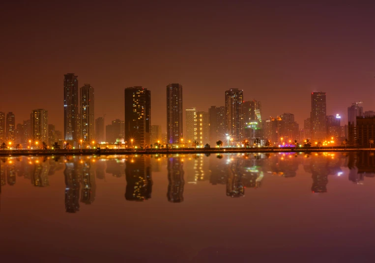 a city skyline at night reflected in a body of water, jeddah city street, foggy lights, pyongyang city, nature photo