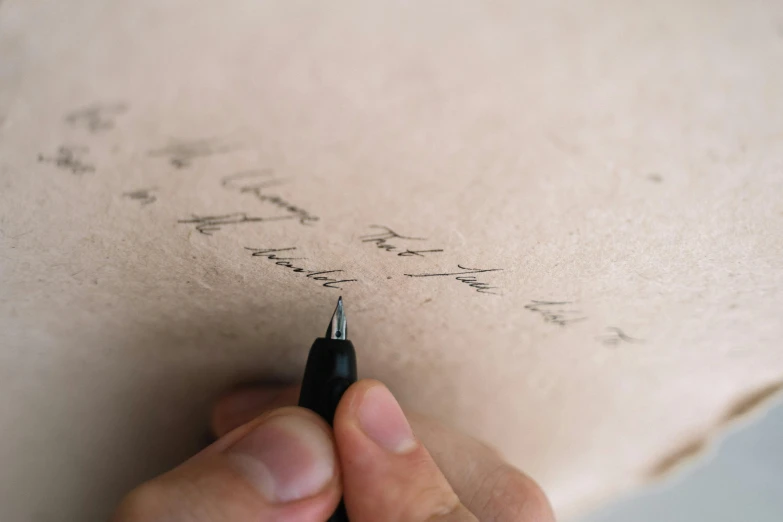 a person writing on a piece of paper with a pen, by Emma Andijewska, unsplash, letterism, cardboard, detailed shading, thumbnail, brown