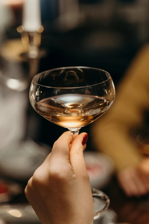 a close up of a person holding a wine glass, zoomed in, champagne, bartending, ultra smooth