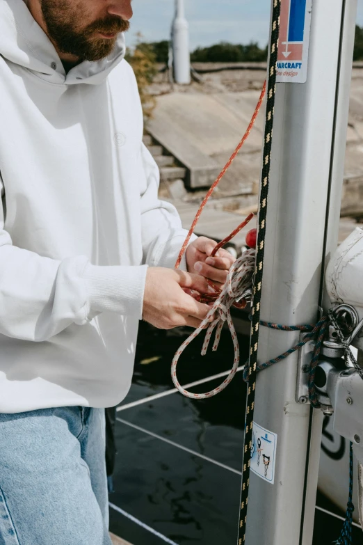 a man standing next to a boat on a body of water, happening, wiring, white sleeves, close up shot from the top, off - white collection