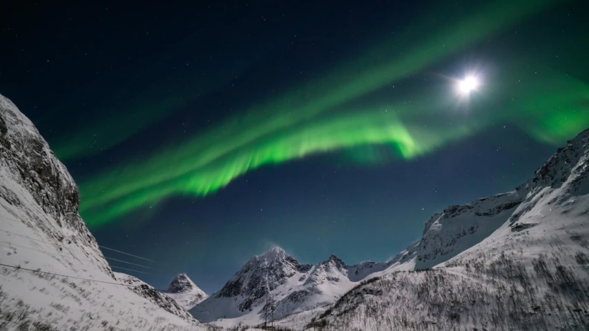 the northern lights shine brightly in the sky above a snowy mountain range, by Anato Finnstark, pexels contest winner, moon beams dramatic light, large glowing moon, norwegian, a green