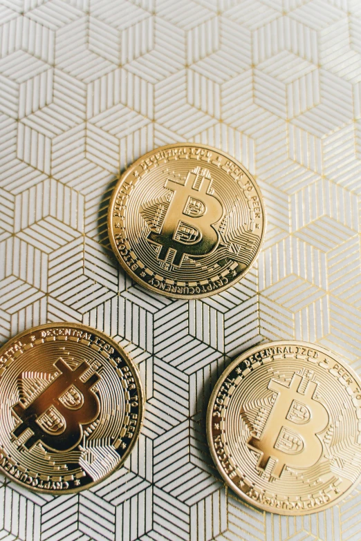 three bitcoins sitting on top of a table, by Adam Rex, trending on unsplash, renaissance, pattern, thumbnail, gold foil, panel