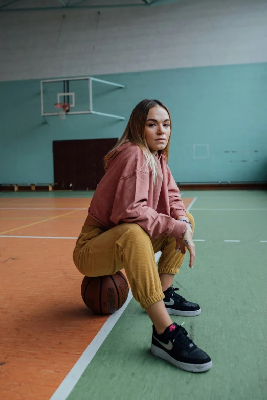 a woman sitting on top of a basketball ball on a court, inspired by Elsa Bleda, trending on dribble, sydney sweeney, pants, schools, low quality photo