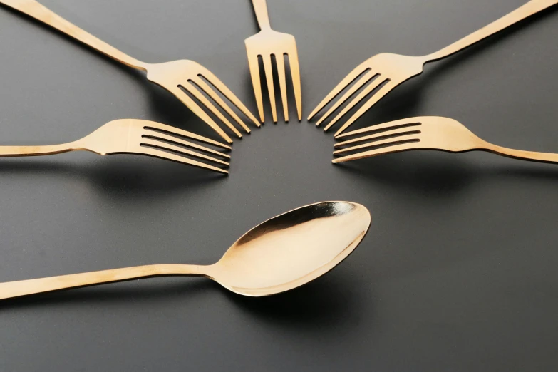 a group of forks and spoons arranged in a circle, an album cover, inspired by Méret Oppenheim, unsplash, smooth gold skin, against dark background, g 7 summit, 5 years old