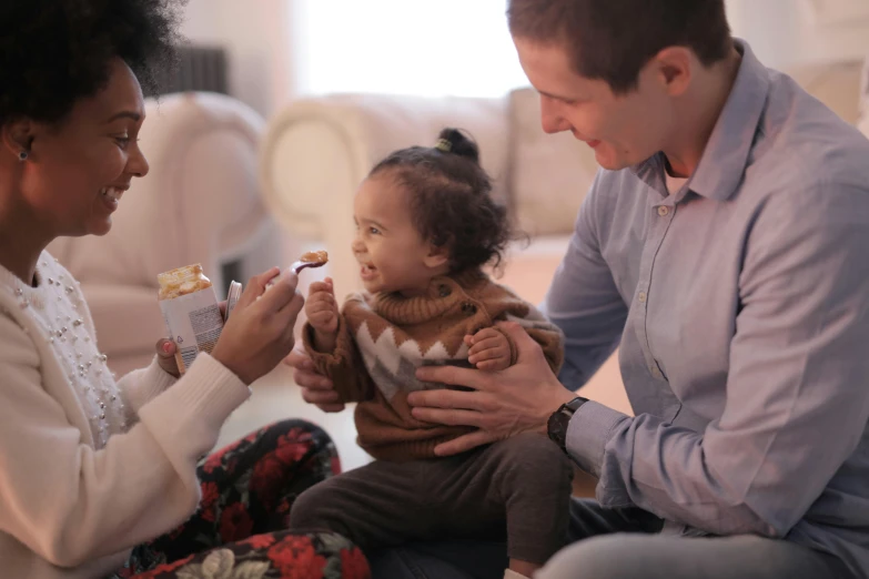 a man and woman feeding a baby while sitting on the floor, pexels, symbolism, manuka, fan favorite, avatar image, giving gifts to people