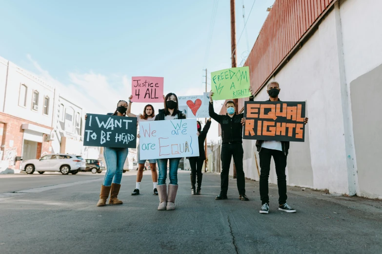 a group of people holding signs on a street, by Julia Pishtar, pexels, brittney lee, rafeal albuquerque, 2 0 2 2 photo, background image