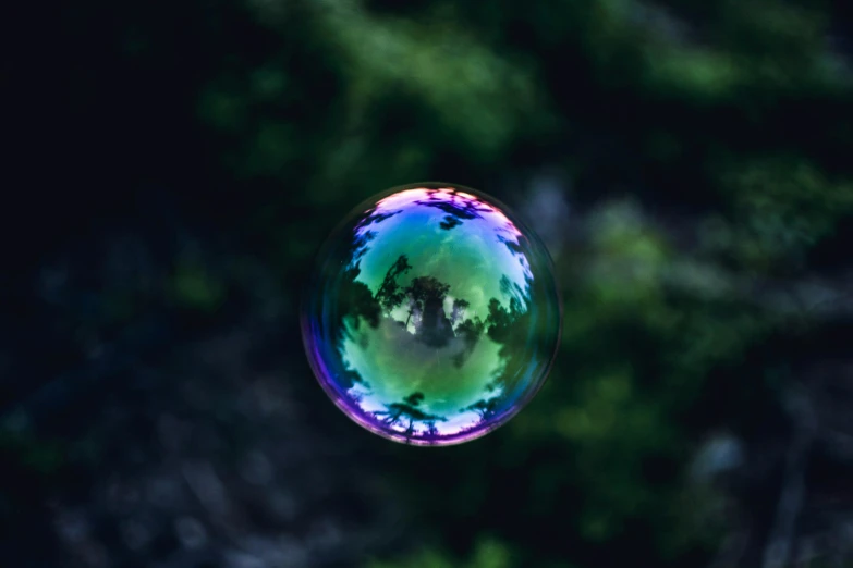 a close up of a soap bubble with trees in the background, pexels contest winner, green and purple, floating. greenish blue, a round minimalist behind, on a gray background