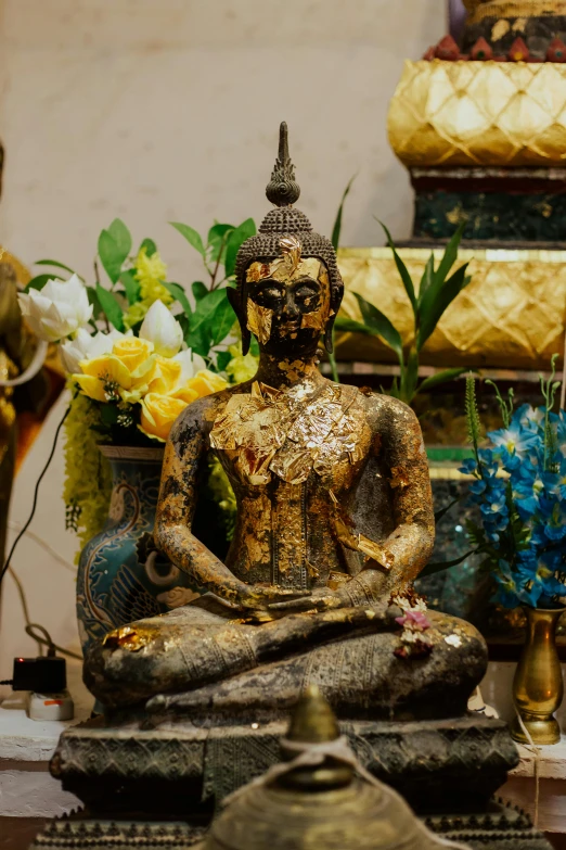 a statue of a person sitting in a lotus position, gold flaked flowers, crafts and souvenirs, looking menacing, serene scene