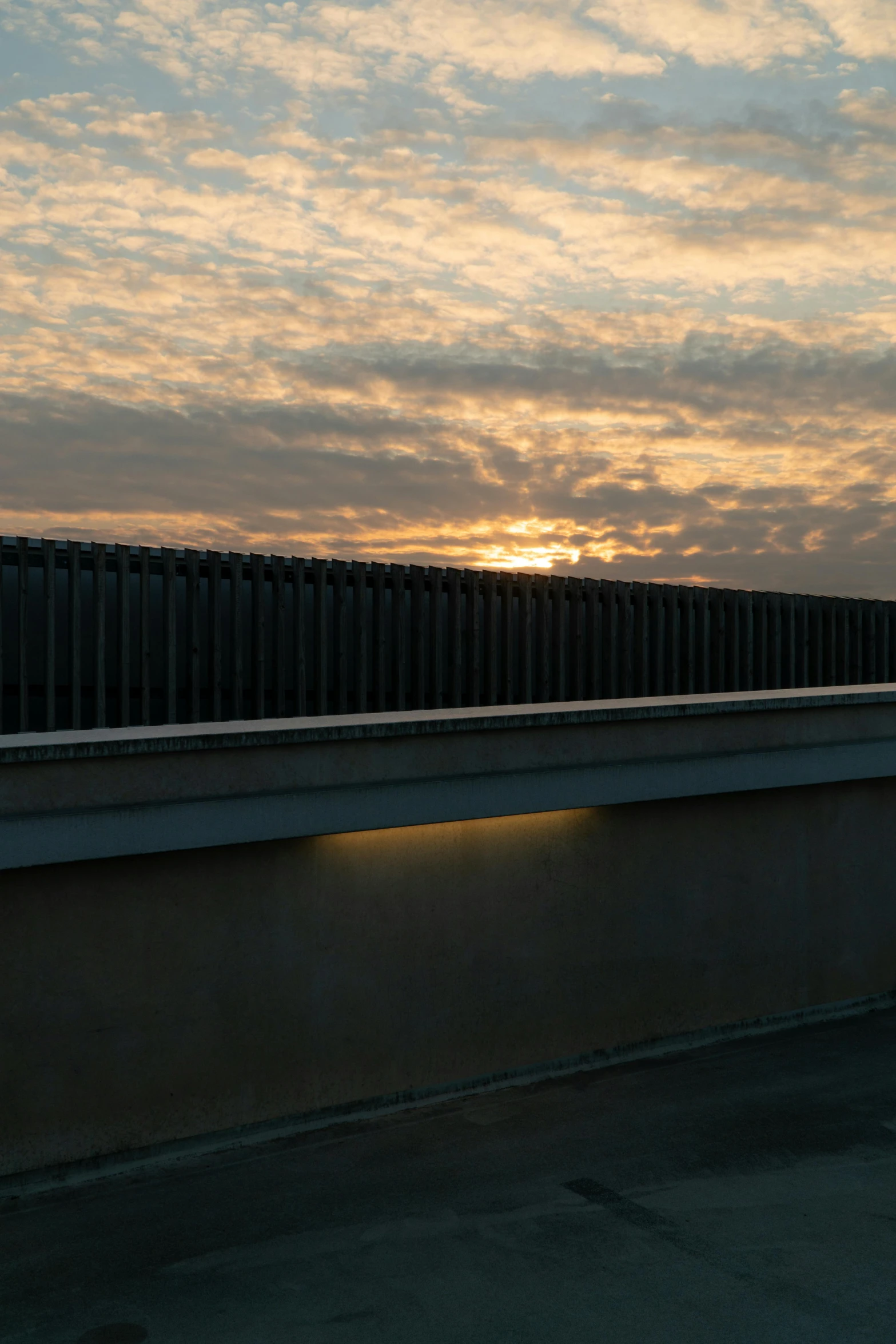 a man riding a skateboard on top of a bridge, a picture, by Jan Tengnagel, early morning sun in the sky, ventilation shafts, sky made of ceiling panels, ((sunset))