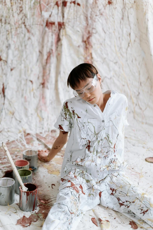 a woman sitting on the ground with paint all over her, a painting, trending on pexels, wearing lab coat and glasses, asian man, on a white table, heavy impasto technique