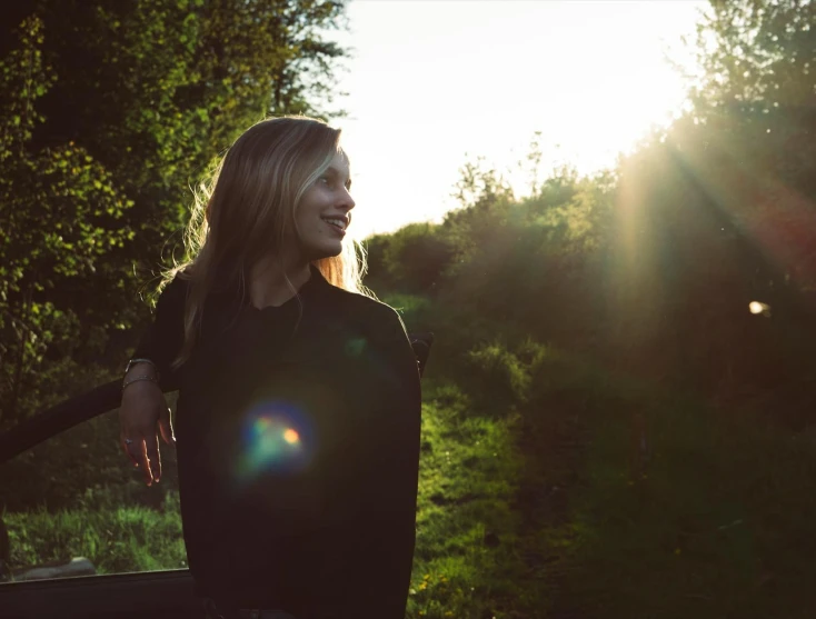 a woman that is standing in the grass, unsplash, happening, glorious light, teenage girl, lit from the side, light smiling