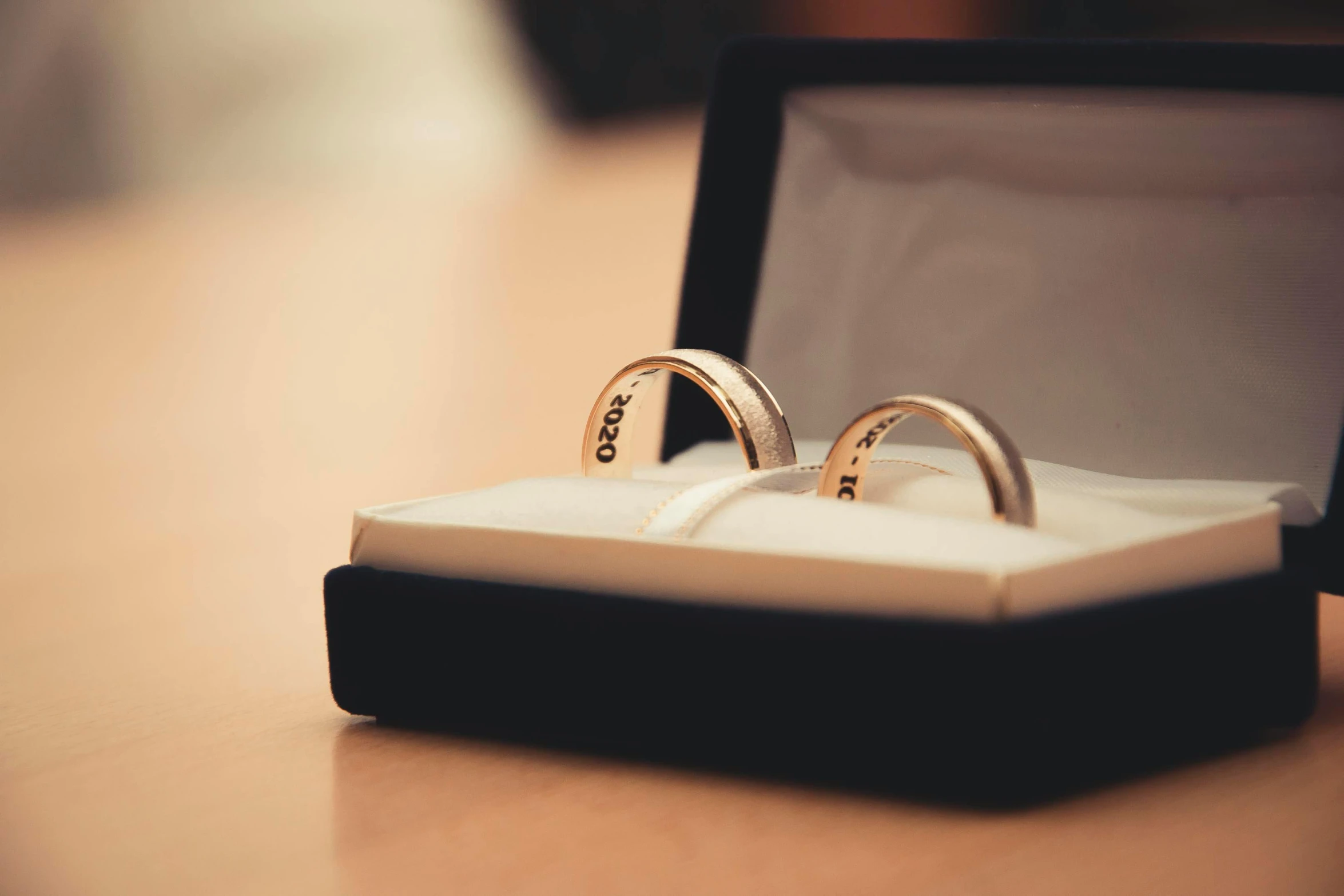 two wedding rings in a box on a table, pexels, private press, engraved, love os begin of all, non-binary, looking left