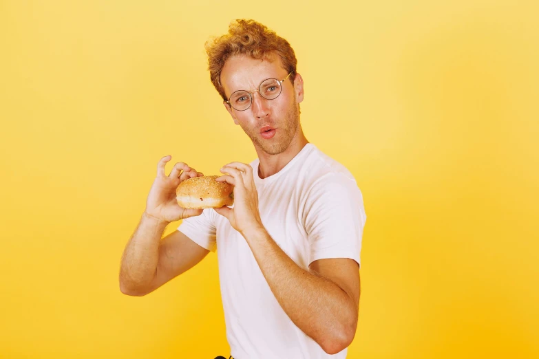 a man holding a donut in front of his face, an album cover, by Lee Gatch, trending on pexels, napoleon dynamite, yellow carrera glasses, model posing, eating a hamburger